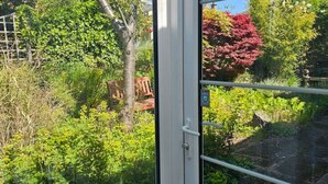 A window with a view of a garden, including various plants and trees. - The Robin House in Ravelston (Edinburgh)