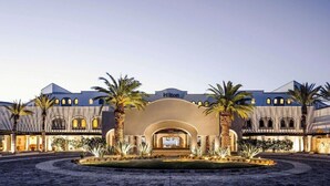 Un hôtel Hilton doté d’une entrée en arc de cercle, de palmiers et d’une cour intérieure.