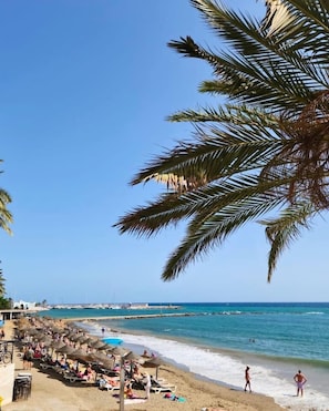 A beach with sun loungers and umbrellas, a clear blue sky, and a calm sea. - Playa de la Fontanilla Marbella (Marbella)