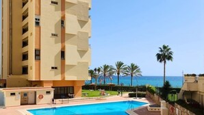 A hotel with a pool area, a clear view of the ocean, and a palm tree-lined promenade. - Playa de la Fontanilla Marbella (Marbella)