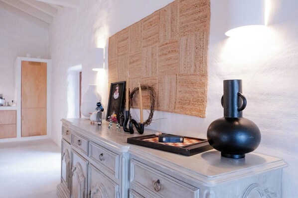 A room with a white dresser, a wall-mounted tapestry, and a black lamp.
