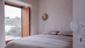 A bedroom with a bed, a window, and a wall-mounted light fixture. - Charming 3-bedroom cottage in Serra d'Aire (Leiria)