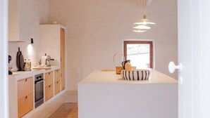 A modern kitchen with wooden cabinets, a central island, and pendant lighting. - Charming 3-bedroom cottage in Serra d'Aire (Leiria)