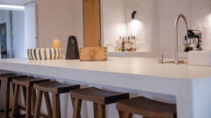 A modern kitchen with a white countertop, wooden stools, a built-in sink, and a wooden cabinet. - Charming 3-bedroom cottage in Serra d'Aire (Leiria)