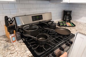 Une cuisine équipée d’une cuisinière, de casseroles, d’une machine à café et d’un ensemble de couteaux.