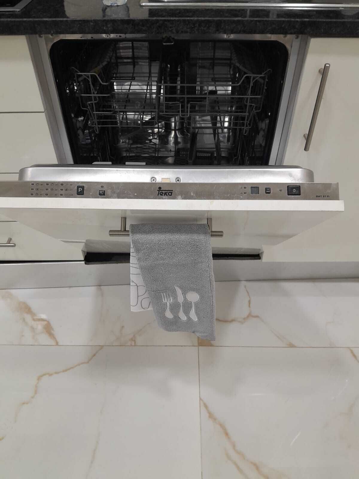 A kitchen with a dishwasher, a towel rack, and a marble countertop.