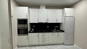 Eine moderne Küche mit weißen Schränken, einer schwarzen Arbeitsplatte, einem eingebauten Backofen, einer Mikrowelle, einem Spülbecken und einem Kühlschrank.