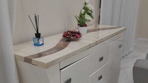 Ein modernes Badezimmer mit Marmorplatte, einem weißen Schrank mit Schubladen, einer kleinen Pflanze und einer Handseifenflasche.