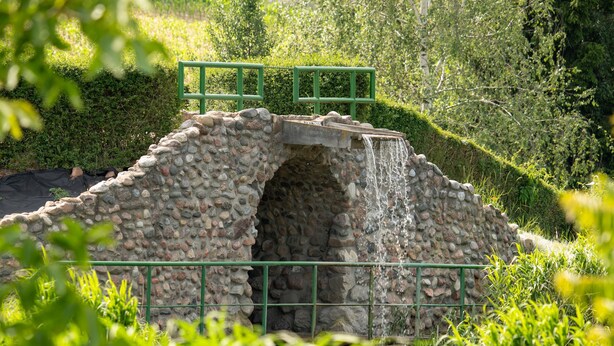 A stone bridge with a small archway, surrounded by lush greenery and a stone wall. - Zatoka Zabłockich Ośrodek Wypoczynkowy (Znin)