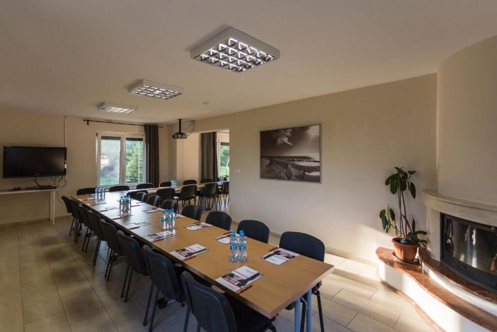 A conference room with a long table, chairs, a flat-screen TV, a fireplace, and a painting on the wall.