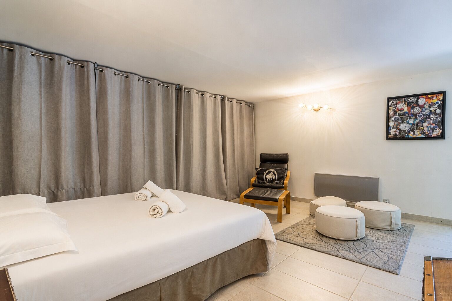 Habitación de hotel con cama, una silla, una mesita y una lámpara de pared.