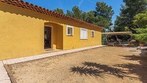 A yellow building with a tiled roof, a covered patio, and a dirt yard. - Villa de L'Uba - Welkeys (Toulon)