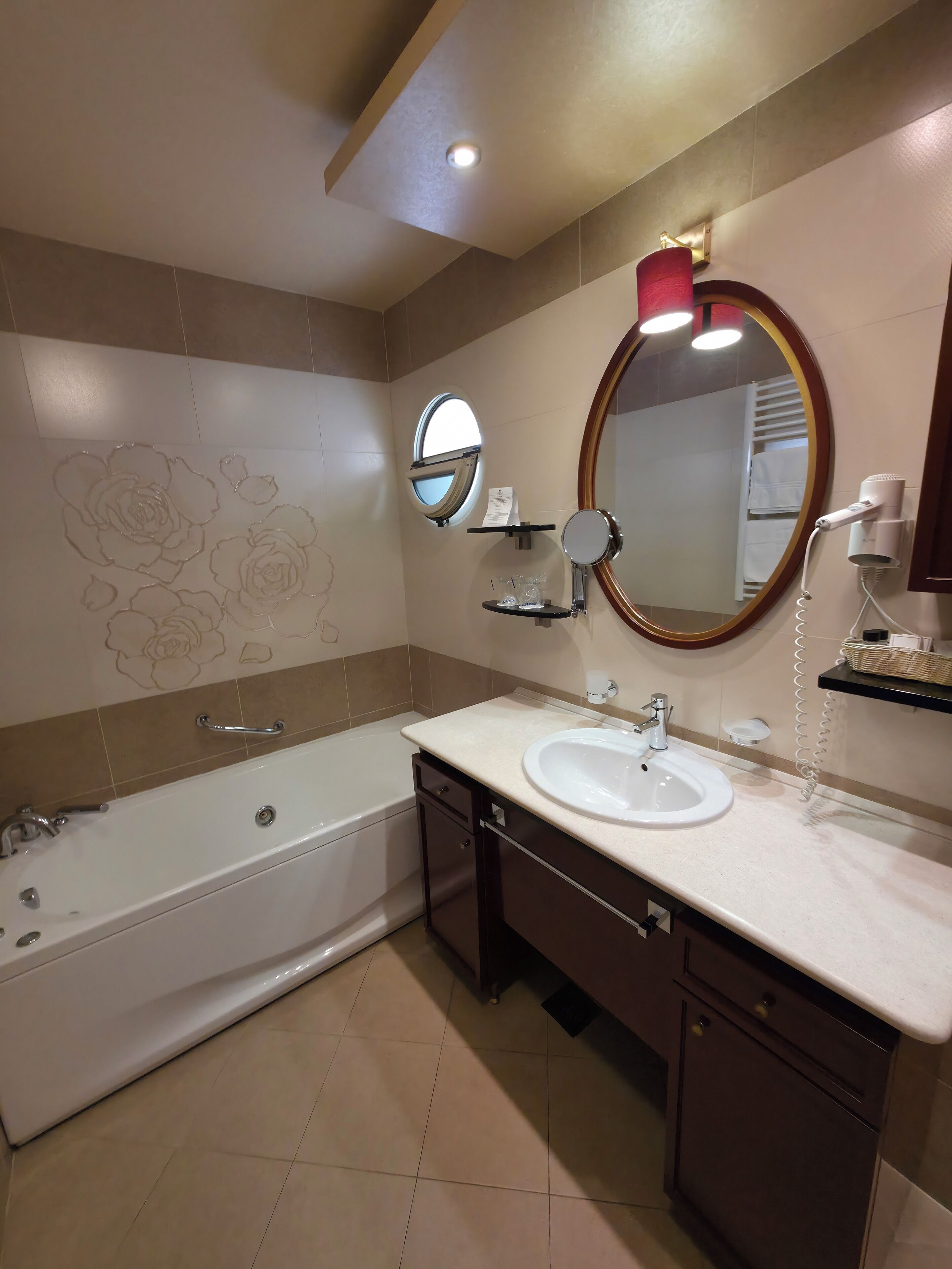Un baño moderno con bañera, lavamanos, tocador con cajones, espejo y toallero.