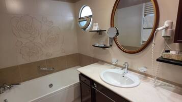 Un baño moderno con bañera, lavamanos, tocador con cajones, espejo y toallero.