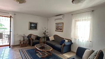 Ein Wohnzimmer mit einer Couch, Sesseln, einem Couchtisch und einem gemusterten Teppich.