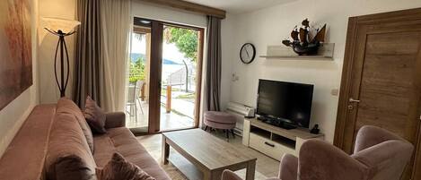 A living room with a sofa, armchairs, a coffee table, a TV, and a door.