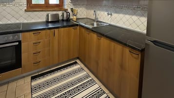 Una cucina moderna con mobili in legno, un frigorifero in acciaio inossidabile, forno integrato e un tappeto a motivi.