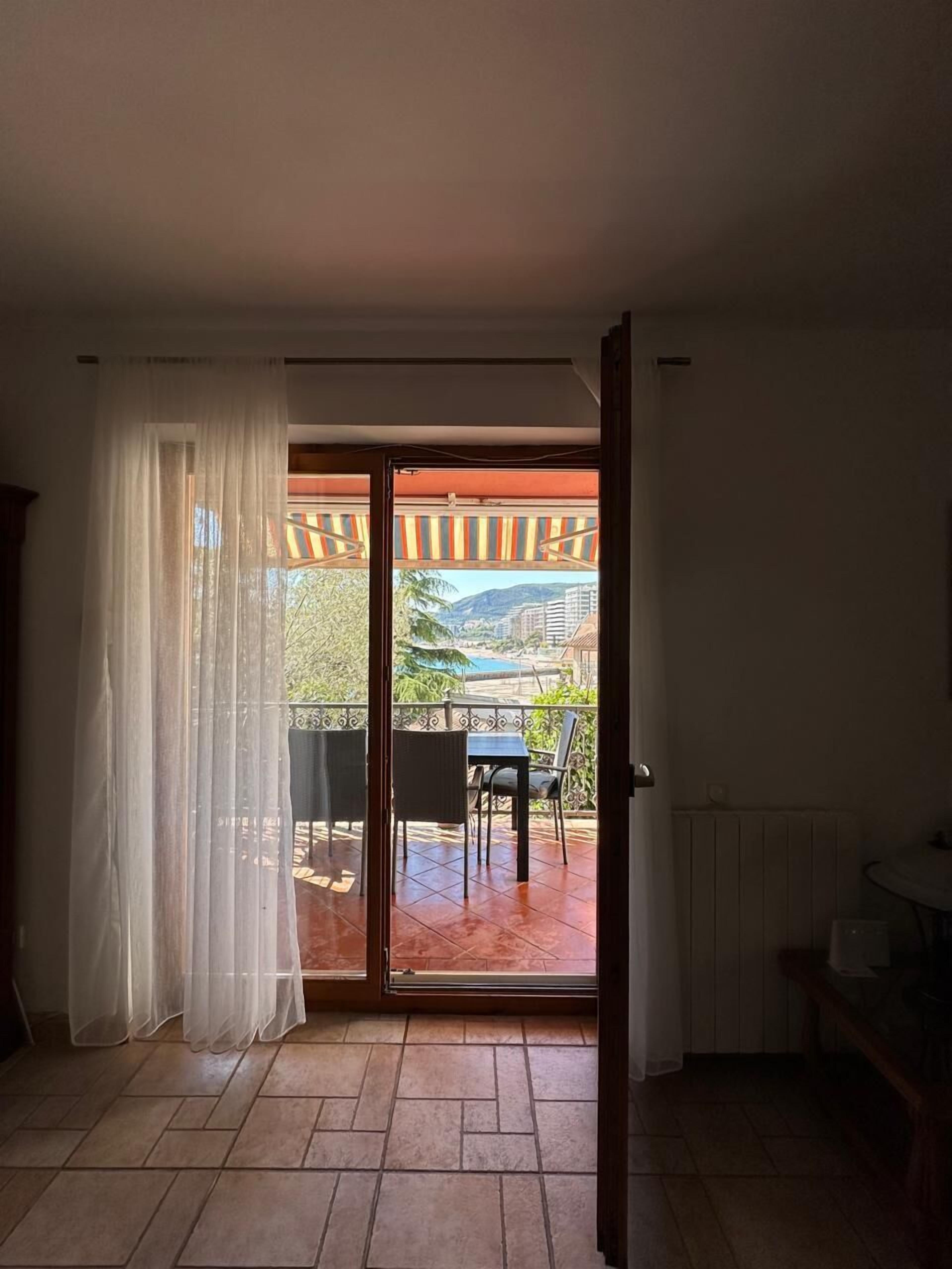 Una habitación con puerta corrediza de vidrio que da a un patio exterior con mesa y sillas.