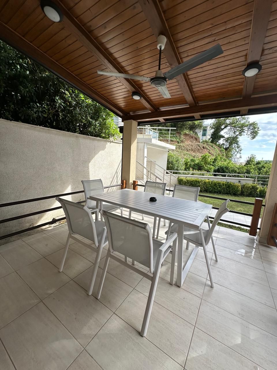 A covered patio with a table and chairs, a ceiling fan, and a view of a hillside.