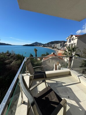 Ein Balkon mit Blick auf eine Küstenlandschaft, einschließlich eines Strandes und Gebäuden.