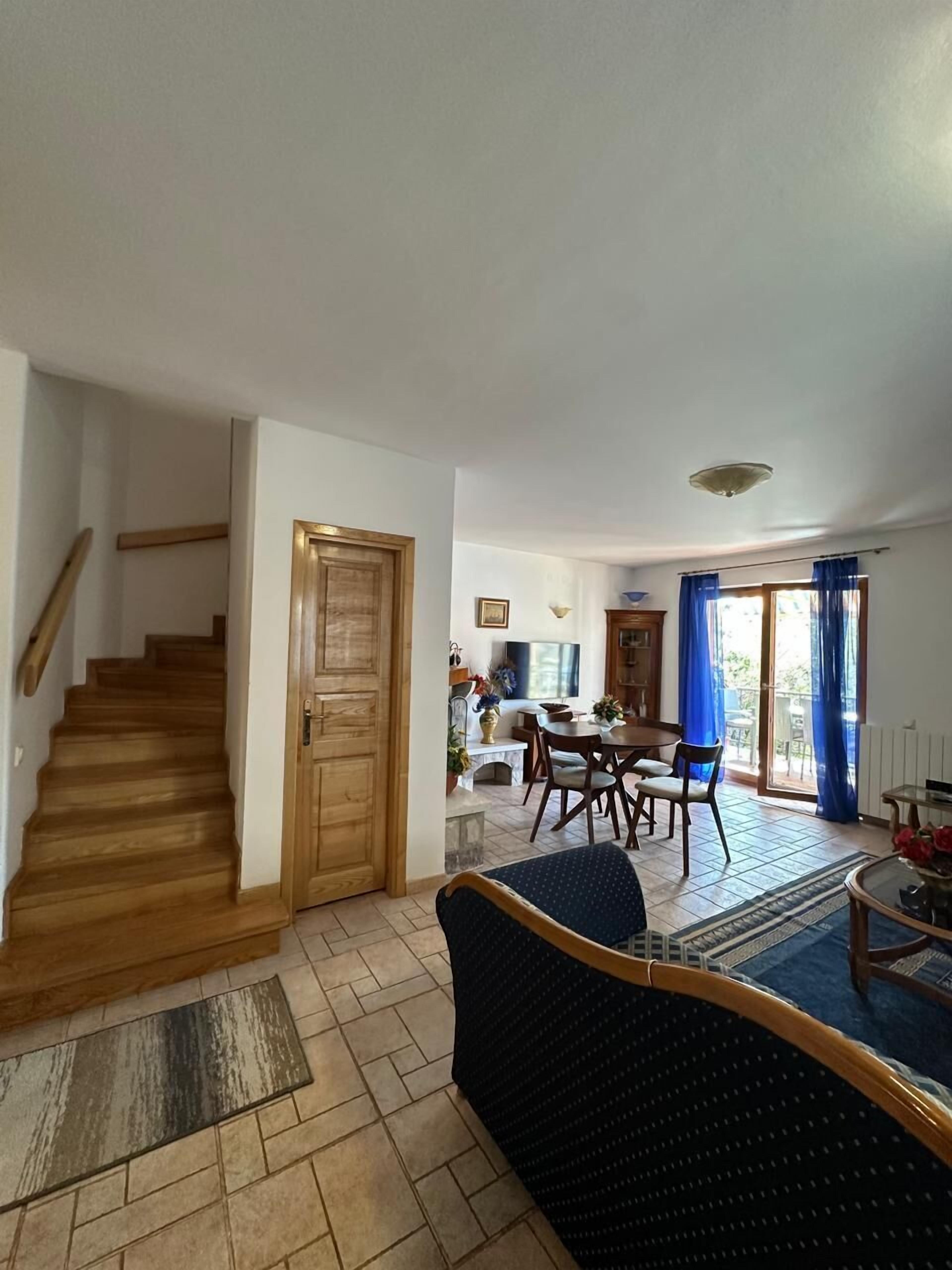 Una sala de estar con una escalera, un comedor y vistas al exterior.