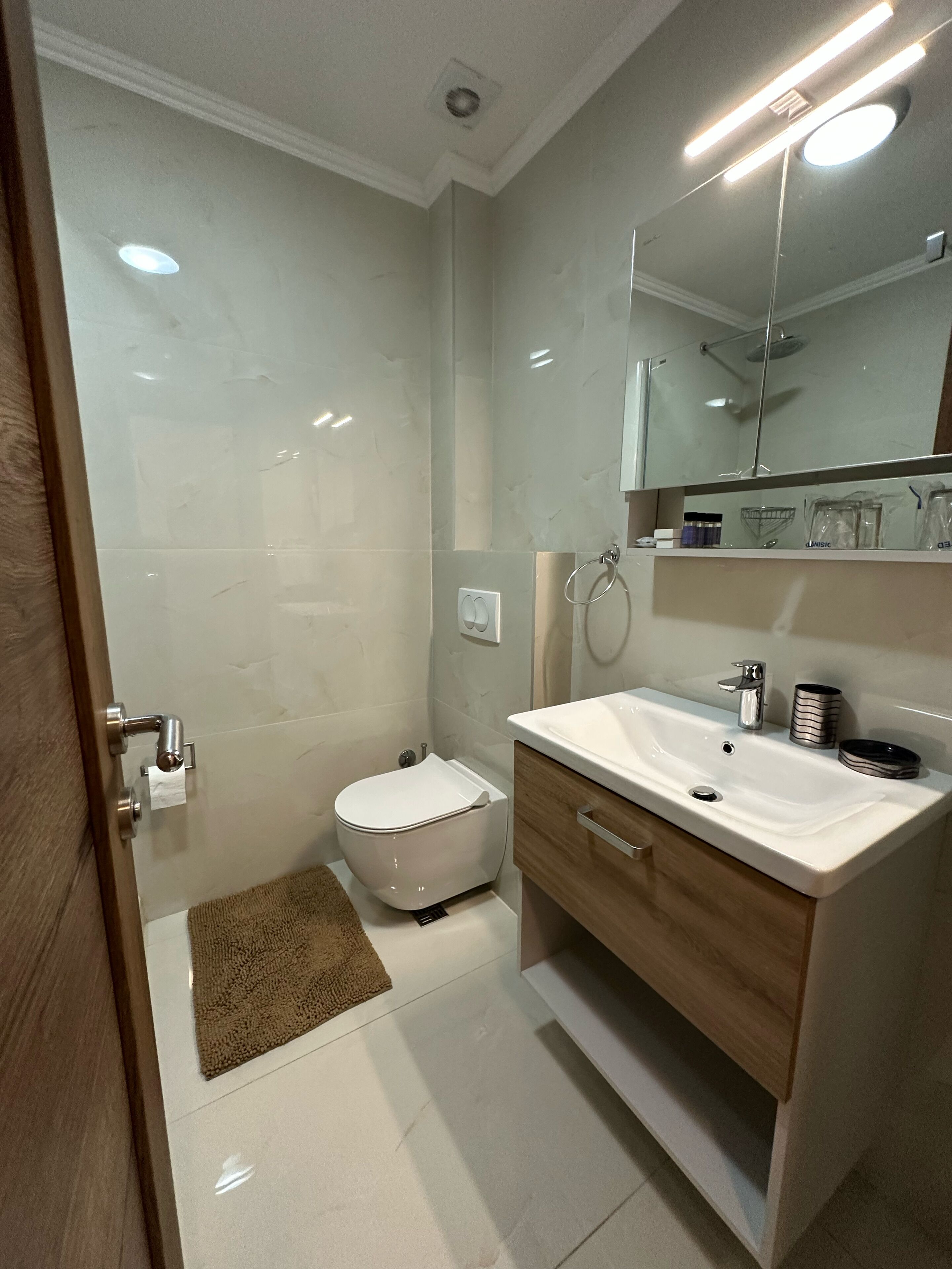 Un baño moderno con inodoro, lavamanos y espejo.