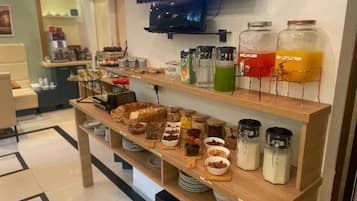 Un bufé de desayuno con diversos alimentos y bebidas en estantes.