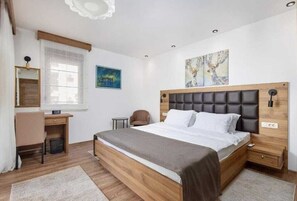 Ein Schlafzimmer mit einem hölzernen Bett, einem Schreibtisch, einem Stuhl und Bildern an den Wänden.