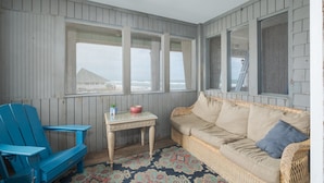 A cozy room with a wicker sofa, a blue chair, and a small table with a bowl and a plant.