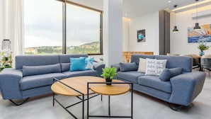 Un salon moderne avec deux canapés, une table basse et un coin repas offrant une vue sur la ville.