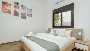 Une chambre à coucher avec un lit, une table de chevet, une fenêtre et des œuvres d’art murales.