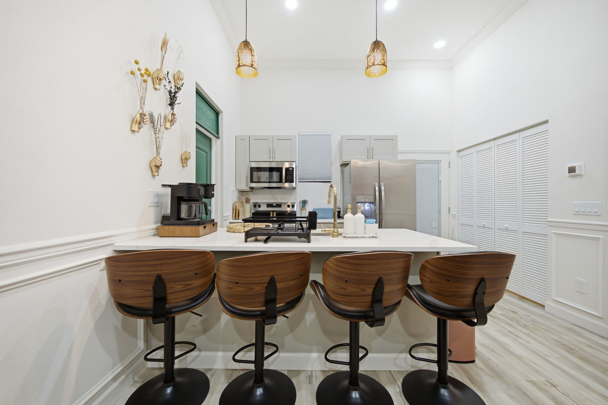 A modern kitchen with a central island, bar stools, and pendant lighting.