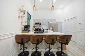 A modern kitchen with a central island, bar stools, and pendant lighting.
