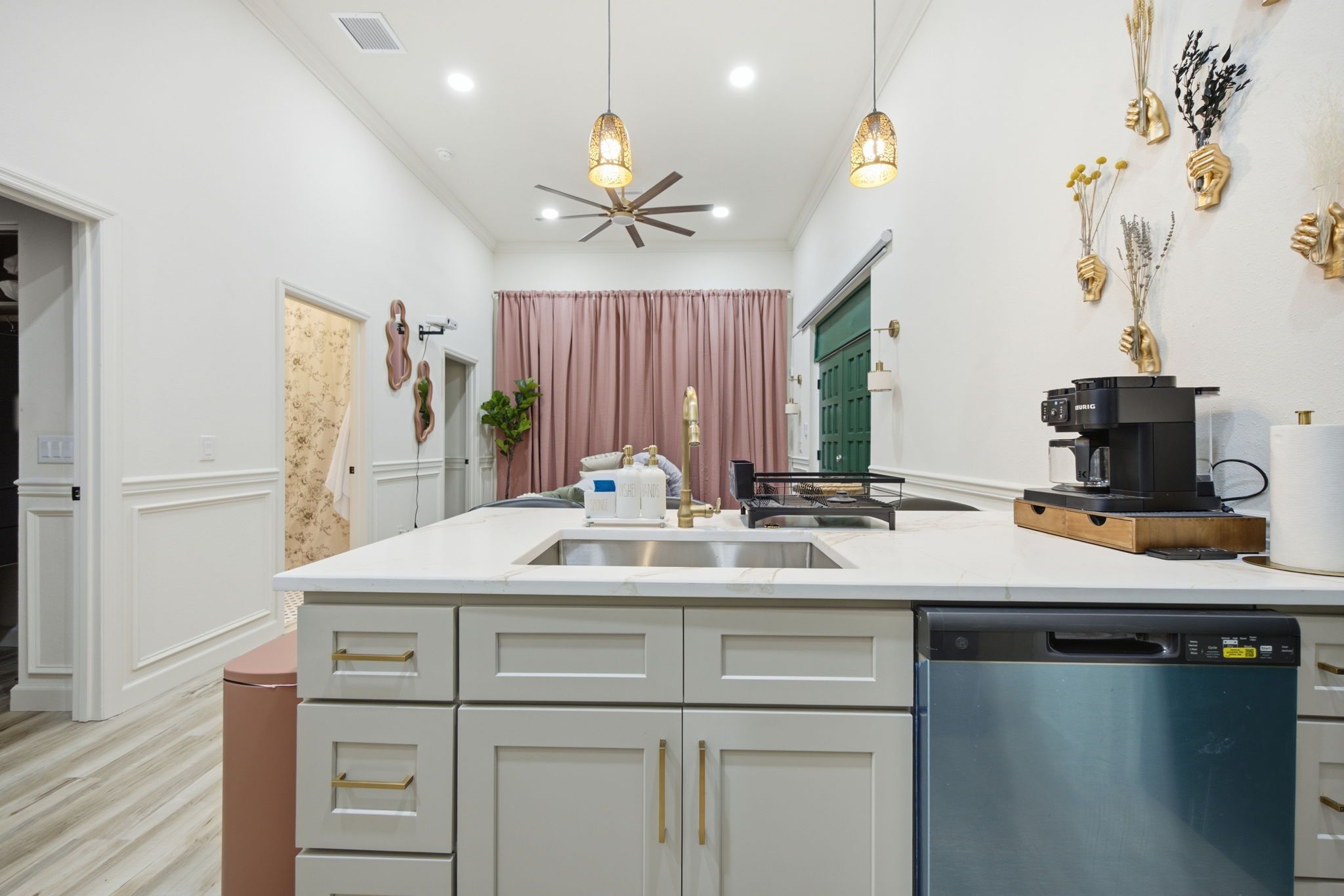 Una cocina moderna con una isla central, armarios blancos, lavavajillas integrado y un ventilador de techo.