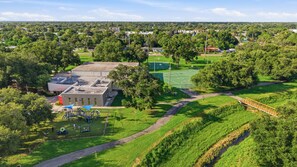 An aerial view of a park with a basketball court, playground, and a building with a flat roof.