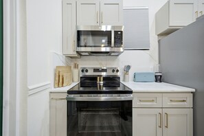A kitchen with white cabinets, a stainless steel microwave, an oven, and a toaster.