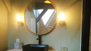 A bathroom with a round mirror, a black sink, and two drawers. - Luxury lakefront dome with private beach, close to nature and town! (Lunenburg)