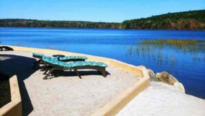 A poolside area with lounge chairs and a clear view of a lake. - Luxury lakefront dome with private beach, close to nature and town! (Lunenburg)