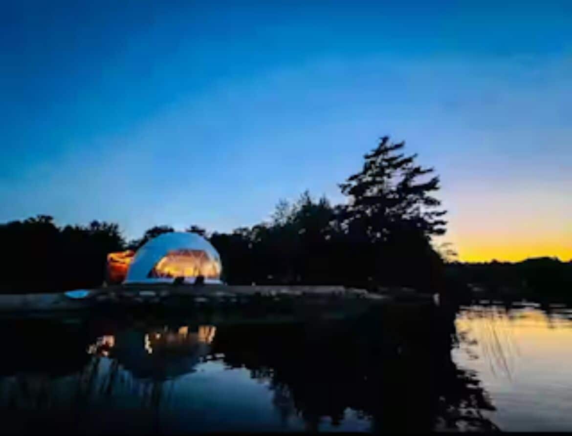 A dome-shaped building by a calm body of water at dusk.
