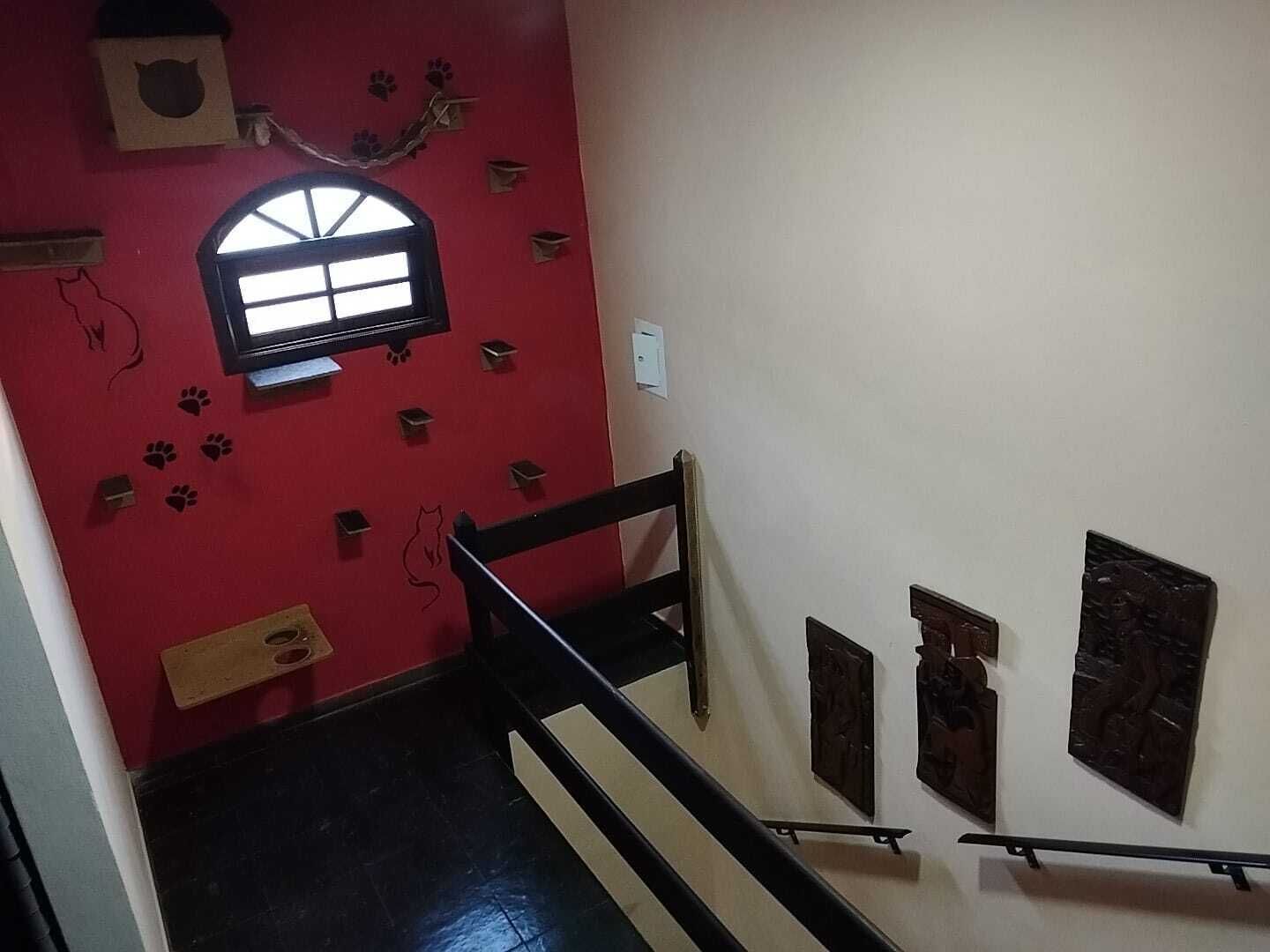 Una escalera con una pared roja, un ventanal pequeño y varias decoraciones en la pared.