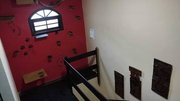 Una escalera con una pared roja, un ventanal pequeño y varias decoraciones en la pared.