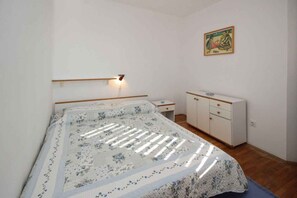 A bedroom with a bed, bedside table, wardrobe, and a painting on the wall.