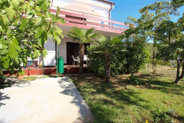 A building with a balcony, a palm tree, and a grassy area.