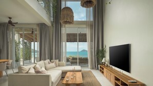 Un salon moderne avec un canapé, une table basse, un téléviseur et de grandes fenêtres donnant sur un paysage magnifique.