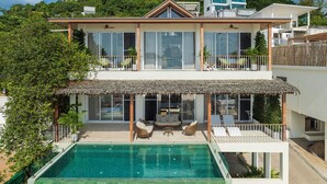 Une maison à deux étages avec une piscine, de grandes fenêtres et un balcon.