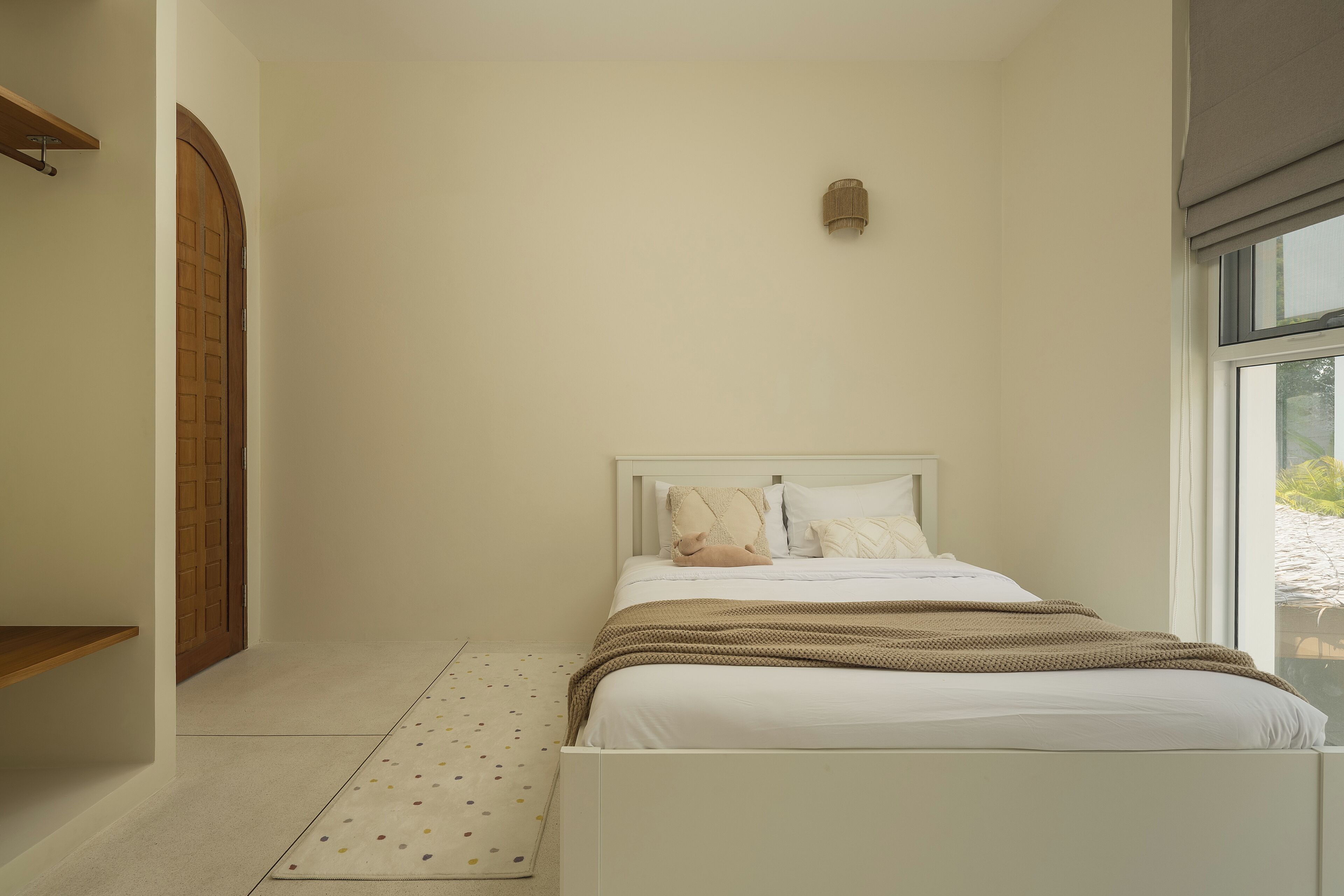 A bedroom with a bed, a window, and a door.
