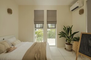 A bedroom with a bed, a potted plant, a chalkboard, and a window with blinds.