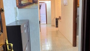 A hallway with a tiled floor, a painting on the wall, and a door with a cabinet. - Charming 2-bedroom apartment with WiFi, AC in superb Fès (Fès)