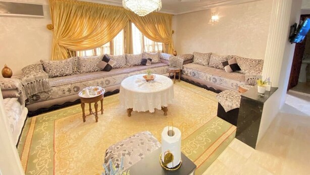 A spacious living room with two sofas, a round coffee table, and a chandelier. - Charming 2-bedroom apartment with WiFi, AC in superb Fès (Fès)