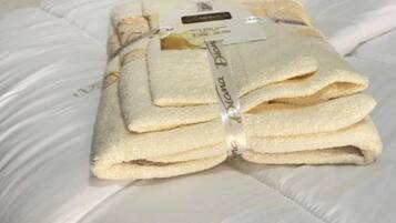 A neatly folded set of towels on a bed with a white cover.